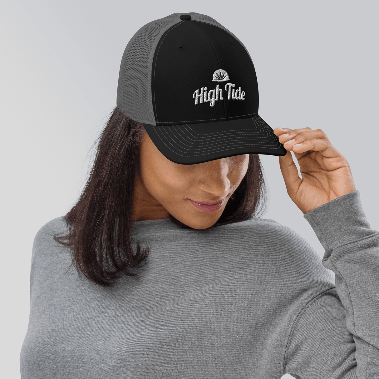 Model wearing High Tide black and grey snapback trucker cap with high tide papers logo