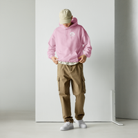 Model wearing High Tide Heart Belongs to the Ocean graphic hoodie, showing the front logo with a white wall backdrop